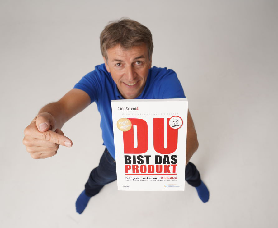 Motivationstrainer Dirk Schmidt mit einem Plakat in der Hand, Schirftzug "DU bist das Produkt"